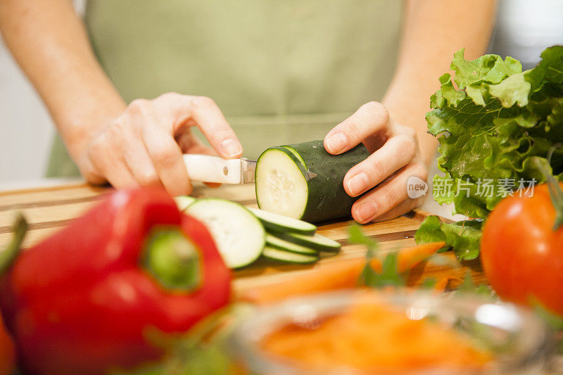 女人在家庭厨房里切黄瓜，蔬菜。
