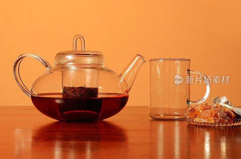 玻璃茶壶和茶杯，桌上放着棕糖
