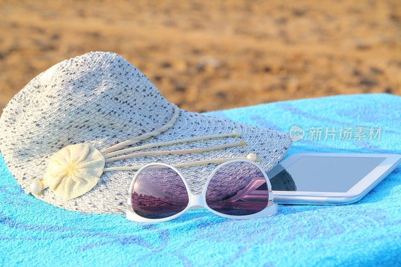 沙滩上的平板电脑和太阳帽
