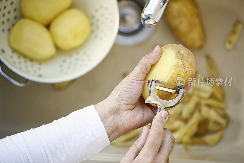 给新鲜的土豆削皮来准备健康的一餐