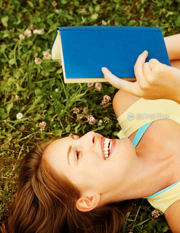 年轻女子躺在草地上看书