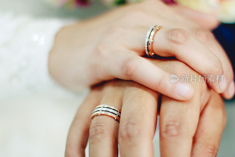 新娘和新郎的手拿着结婚戒指