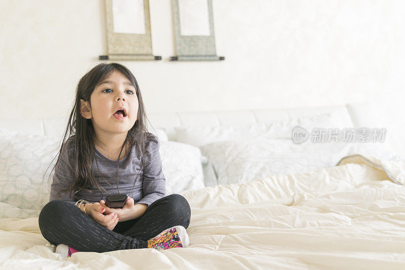 小女孩在父母的床上看电视