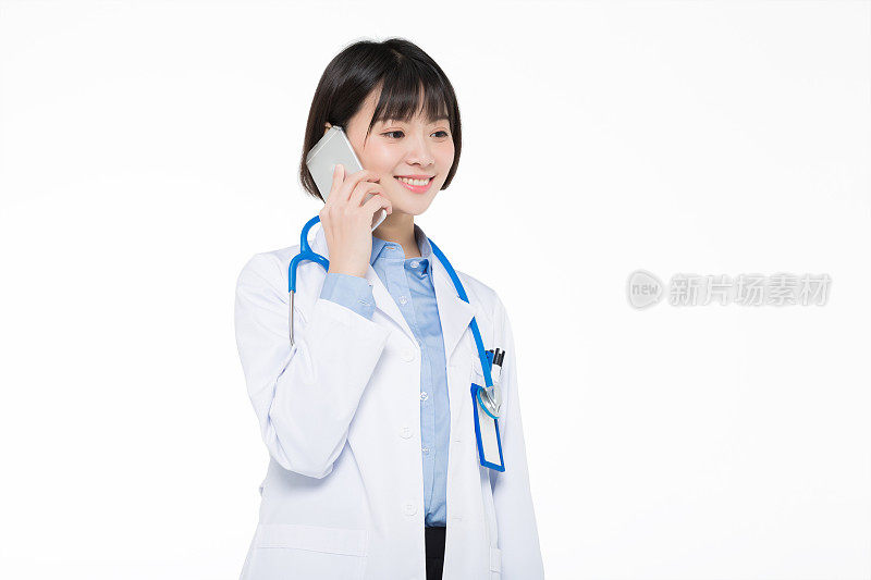 年轻的微笑女医生讲手机孤立在白色的背景