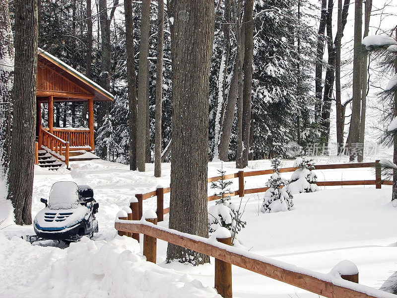 森林里白雪覆盖的小屋和雪地摩托