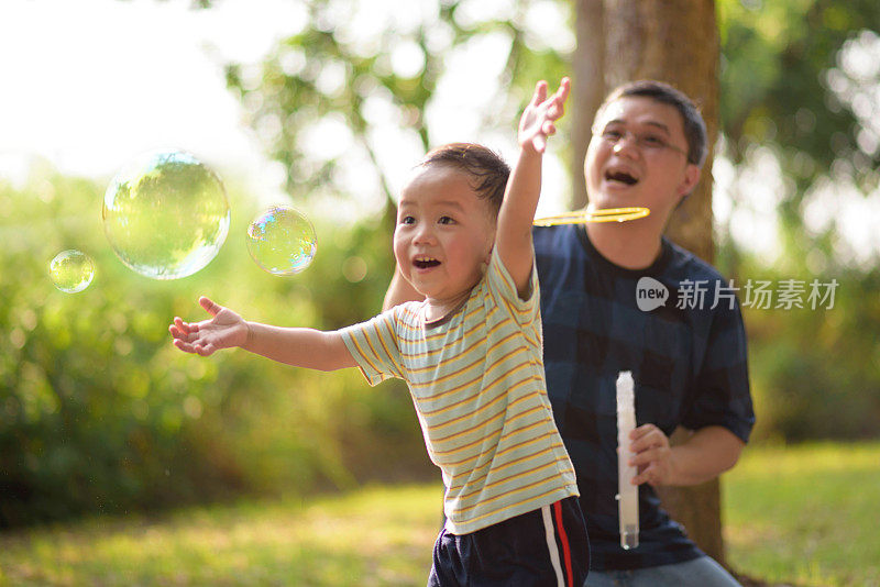 亚洲小孩和父亲玩泡泡棒