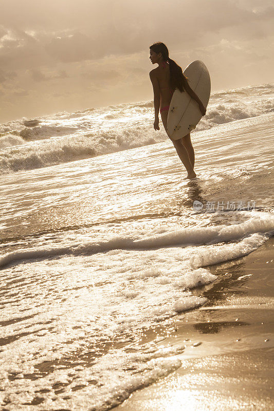 女子比基尼冲浪者和冲浪板日落海滩