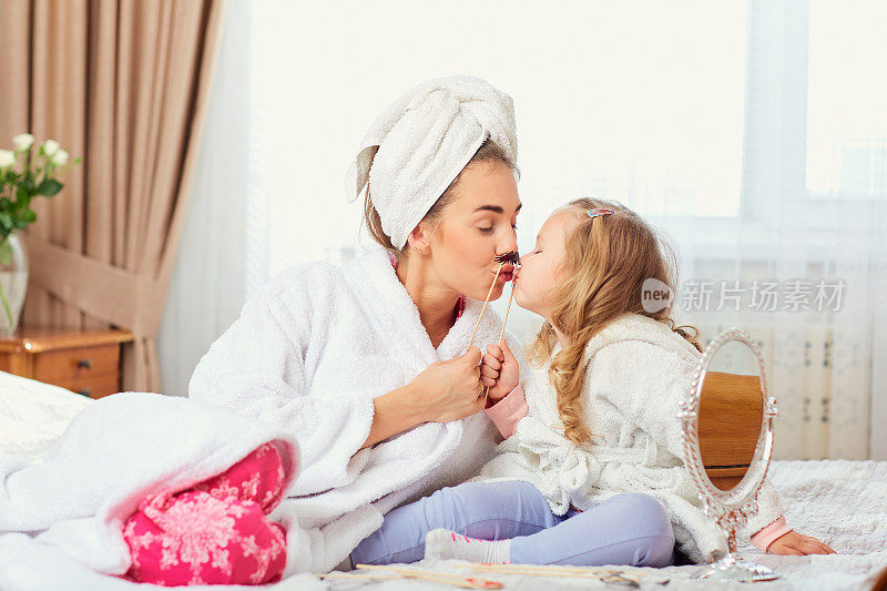 母亲和女儿穿着浴衣和毛巾在ro的床上