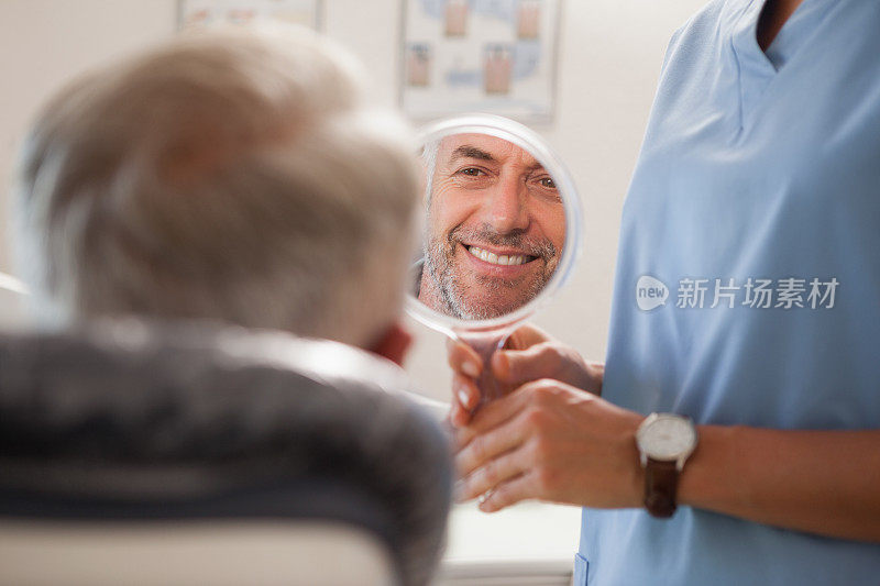 牙医对着镜子向病人展示他的新微笑