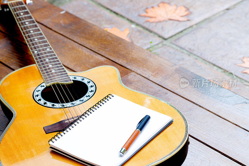 木背景上有笔记本和钢笔的原声吉他
