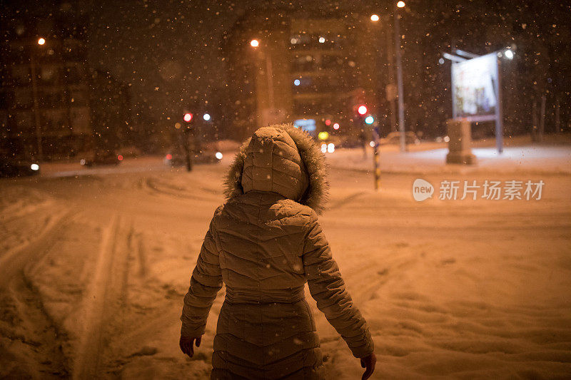 一个女人在下雪的晚上散步