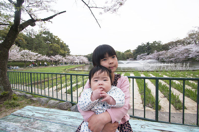 春天里，小女孩和婴儿坐在公园里