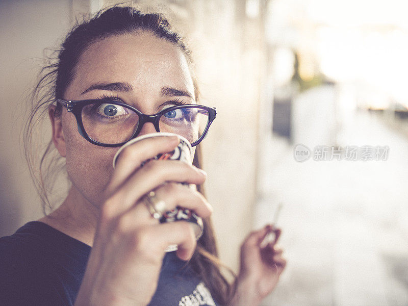 一个女孩喝咖啡和看着相机的特写肖像