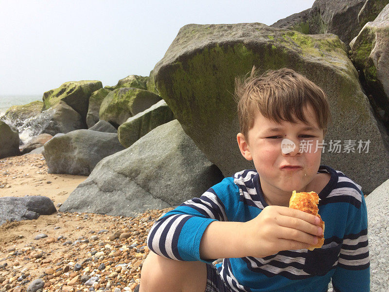 六岁男孩在海滩上吃午饭