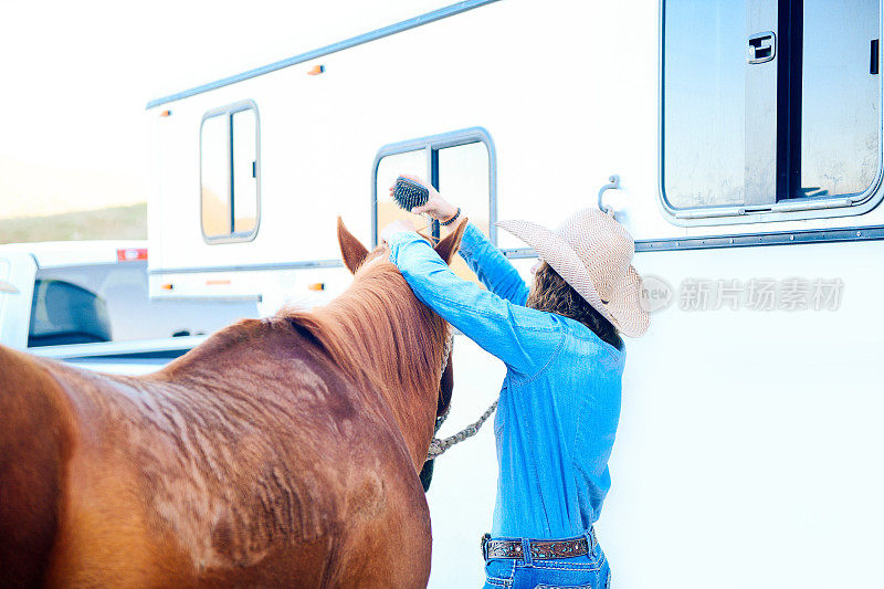 年轻女子戴着牛仔帽梳理她的马梳头发