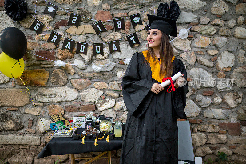 肖像特写美丽的毕业生毕业的学生女孩年轻的女人在帽子长袍显示持有文凭庆祝毕业典礼的概念