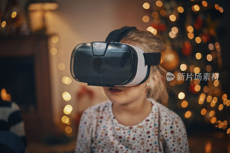 在舒适的圣诞氛围中，小女孩在客厅玩VR眼镜