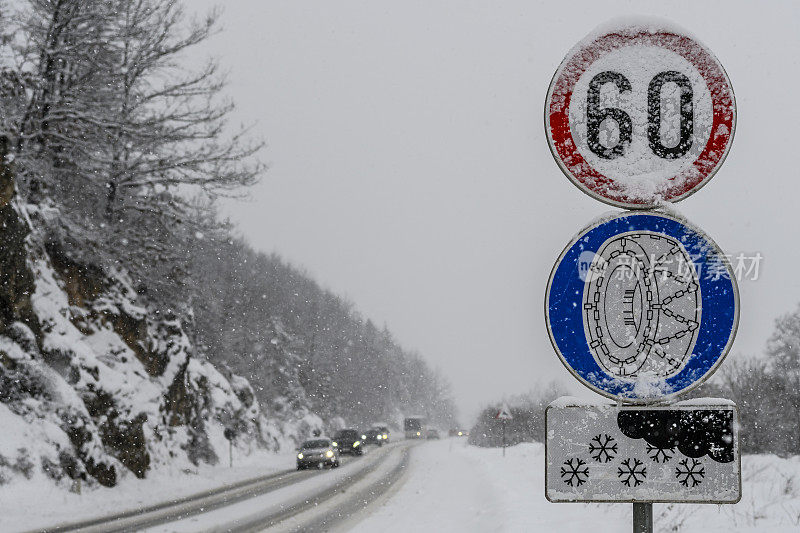 冬天蜿蜒的道路上有限速的雪链标志