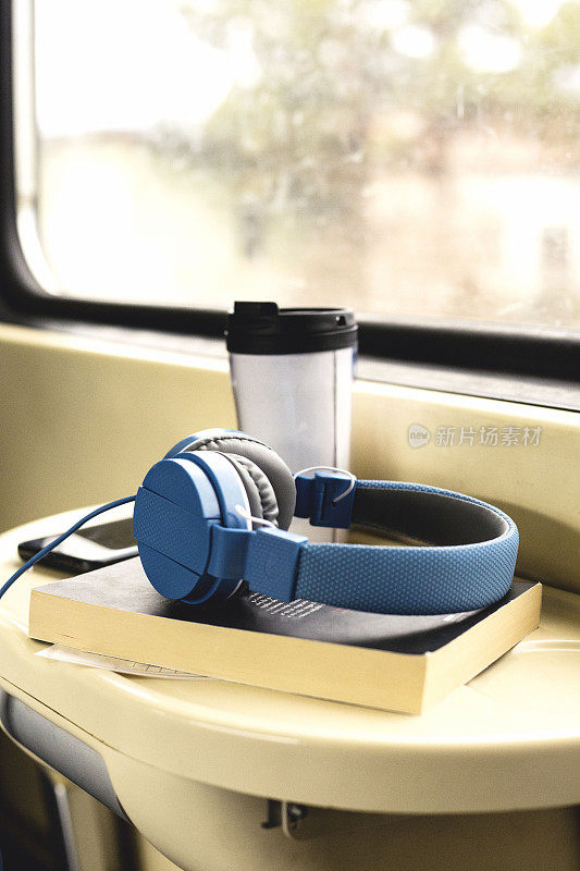火车上的桌子上有耳机、书和咖啡