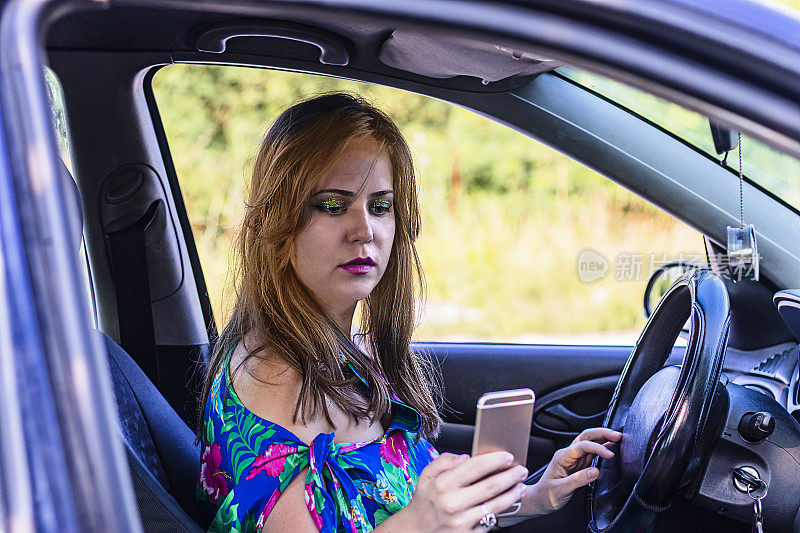 手里拿着手机的女人坐在车里发短信