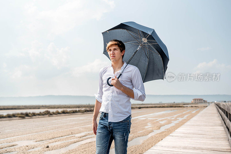 一个年轻人在木栈桥上撑着伞