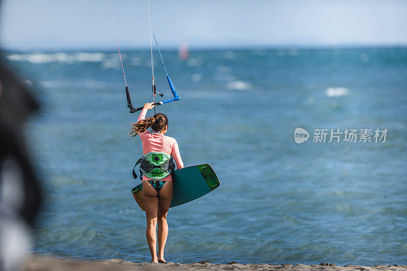 海滩上一个女性风筝冲浪者的后视图。