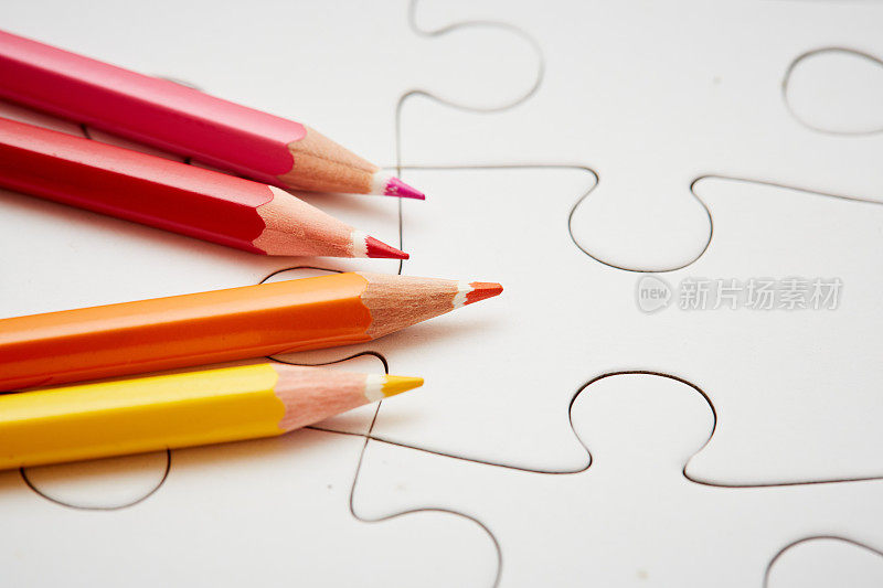 四支彩色铅笔在一个空白的白色拼图上