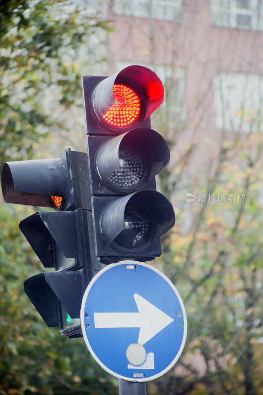 红色交通灯和箭头路标，城市街道。