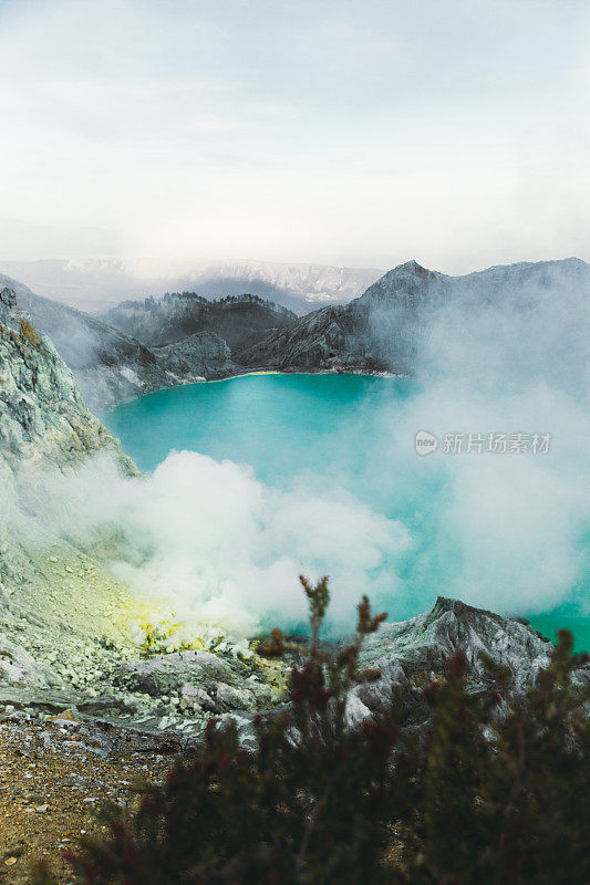 印度尼西亚东爪哇的伊真火山火山口的绿松石色湖泊，山脉和硫磺蒸汽的戏剧性景色