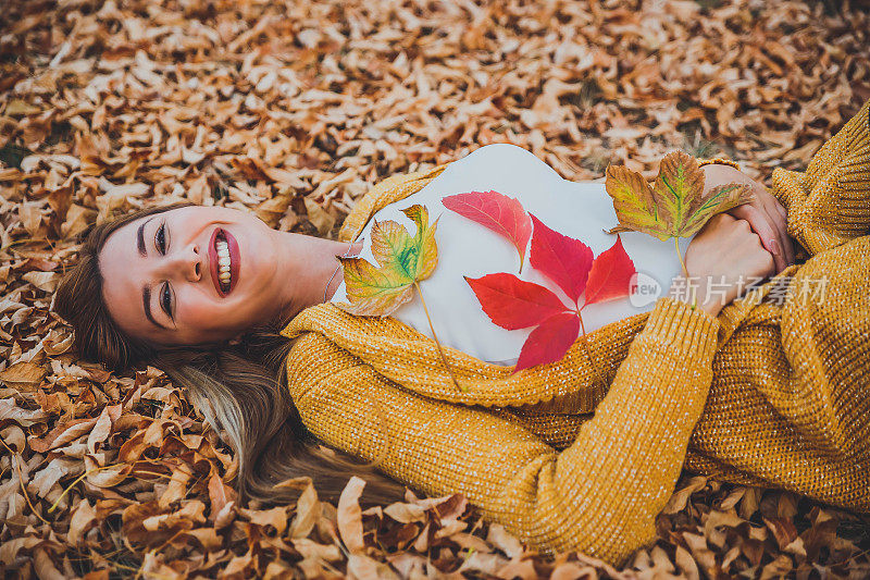 幸福的女人躺在落叶上