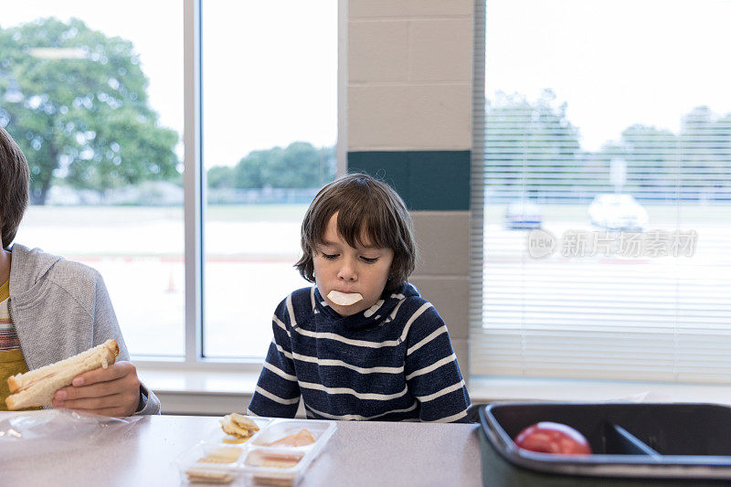 一个学童午餐时吃饼干打发时间