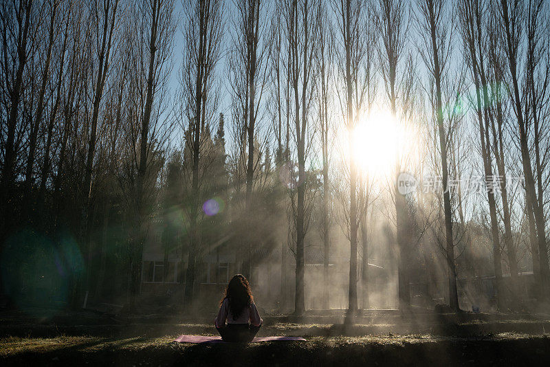 成年妇女在雾蒙蒙的户外做瑜伽练习