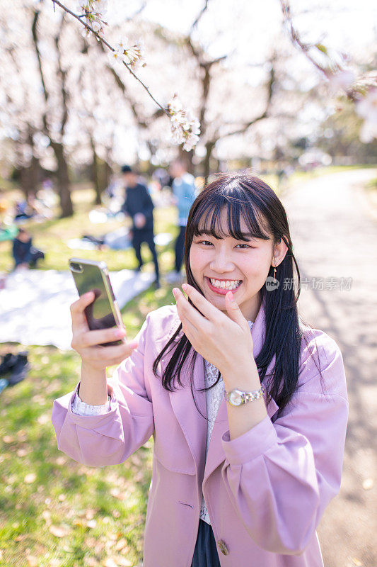 快乐的年轻女子站在樱花下