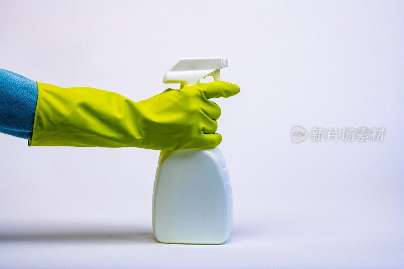 戴着手套，用白色不透明喷雾瓶喷洒消毒剂清洁剂