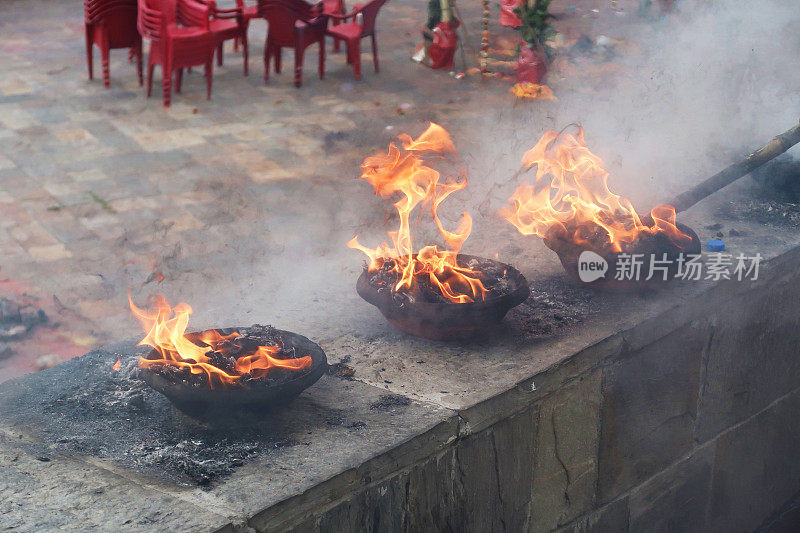 三个印度火碗排列在墙上，燃烧着传统节日的柴火