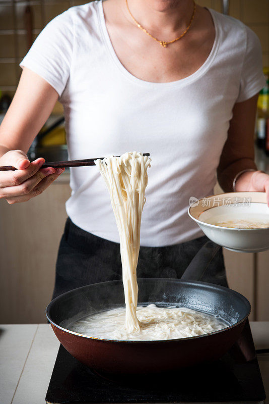 女人在家里煮面条