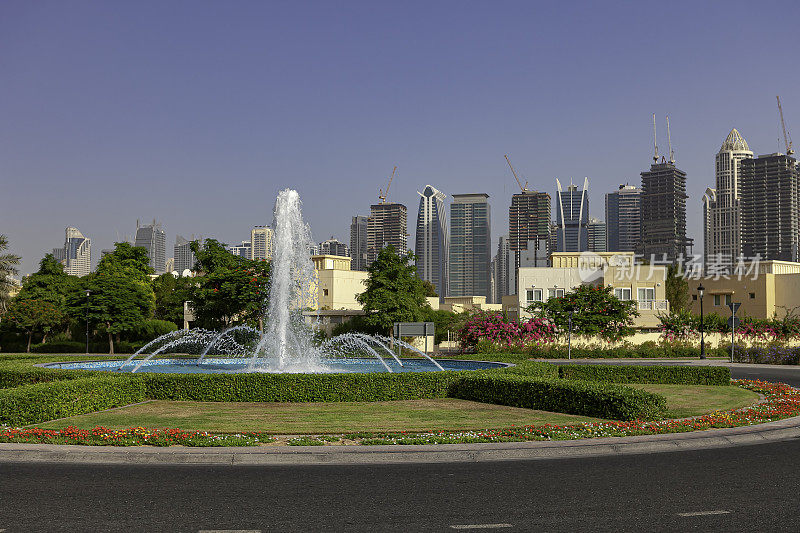 迪拜，阿拉伯联合酋长国-俯瞰喷泉和路边景观，在草地地区，朱美拉湖塔;许多将成为摩天大楼的塔楼仍在建设中