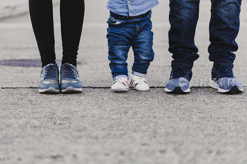 幸福时尚的父母牵着小男孩走在街上，温馨的家庭时刻。
