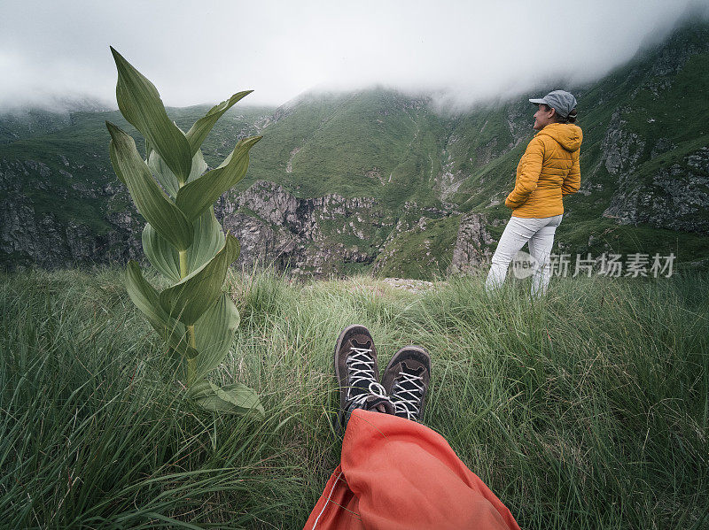 从个人角度看一个人，脚在框架里。回归自然。徒步旅行的游客夫妇在山上看美丽的景色。2019冠状病毒病大流行后的夏日户外享受。社会距离。