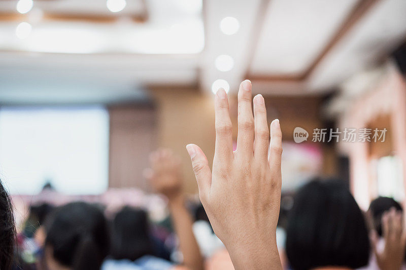 听众或学生在会议上举手回答问题，而演讲者在研讨会大厅与人群演讲，教室里的大群手臂进行投票或提问