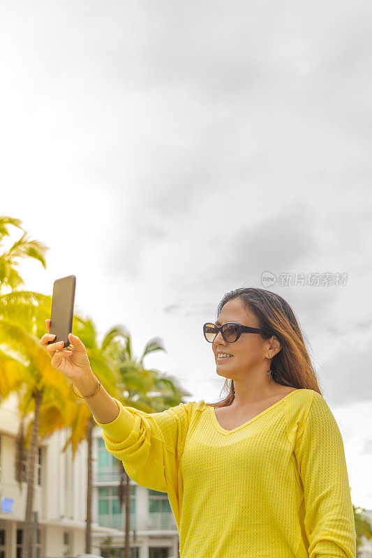 美国佛罗里达州迈阿密海滩，一名年轻女子正在用智能手机拍照