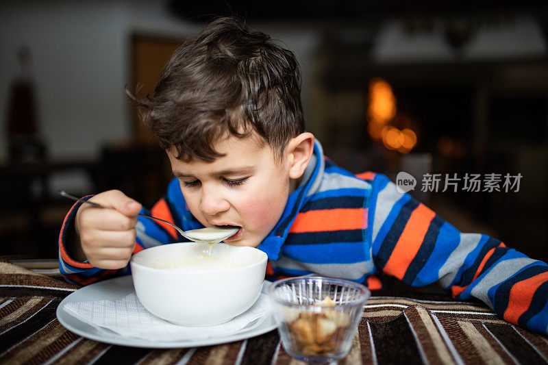 一个可爱的男孩在滑雪小屋喝汤