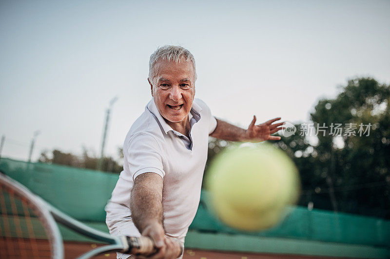 一个活跃的老年人在室外网球场上打网球