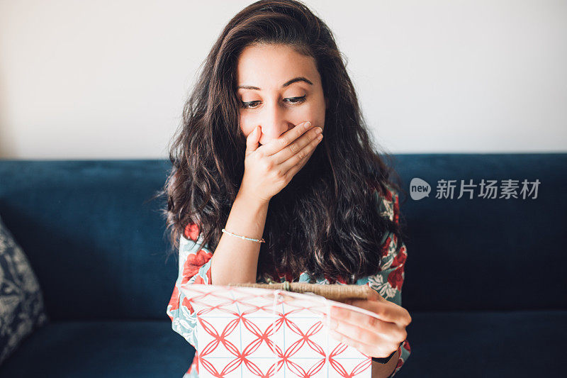 女人打开她的礼物，感到惊讶