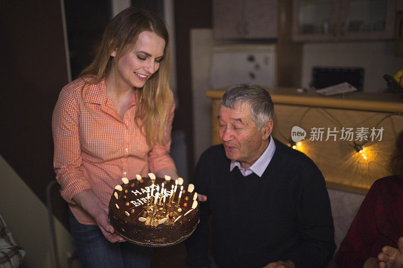 爷爷在家里吹蜡烛庆祝生日