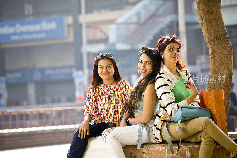 三个女人拿着购物袋坐在城里