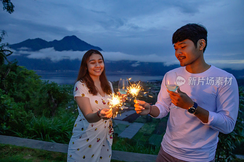 一对印度尼西亚夫妇用闪亮的烟花和葡萄酒庆祝新年前夜