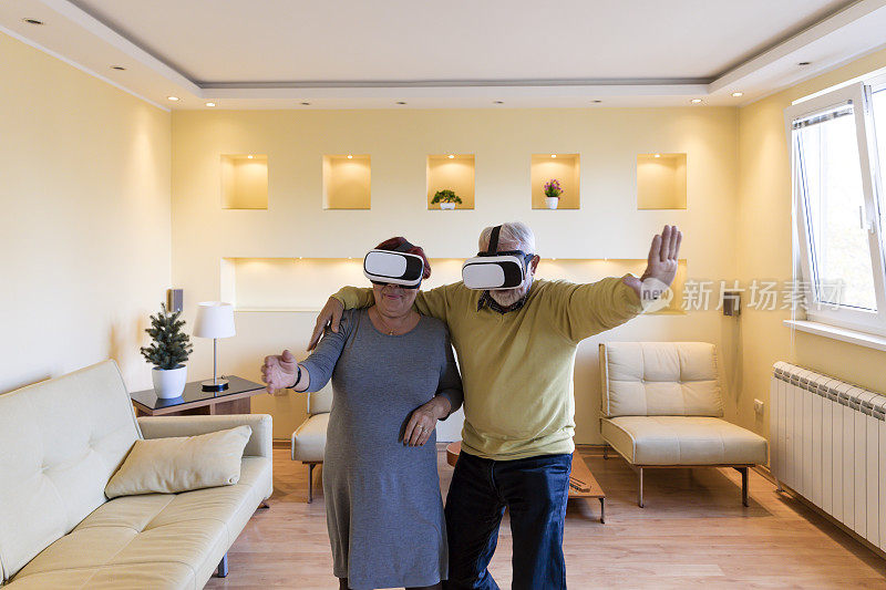 兴奋的老年夫妇正在体验虚拟现实模拟器与VR眼镜游戏。