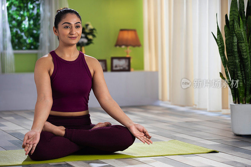 美丽迷人的年轻女人在家里做瑜伽锻炼，健康概念，健身概念，库存照片