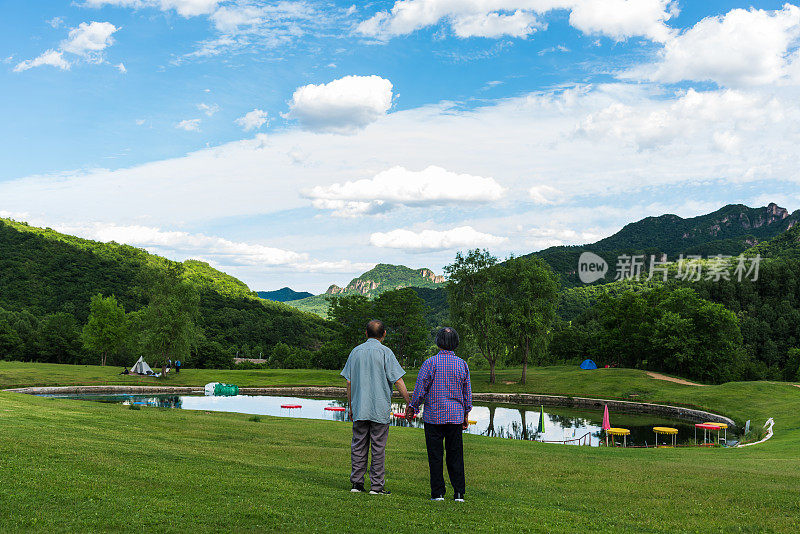 在北京的一个自然公园里，两位中国老人手牵着手欣赏风景的背影